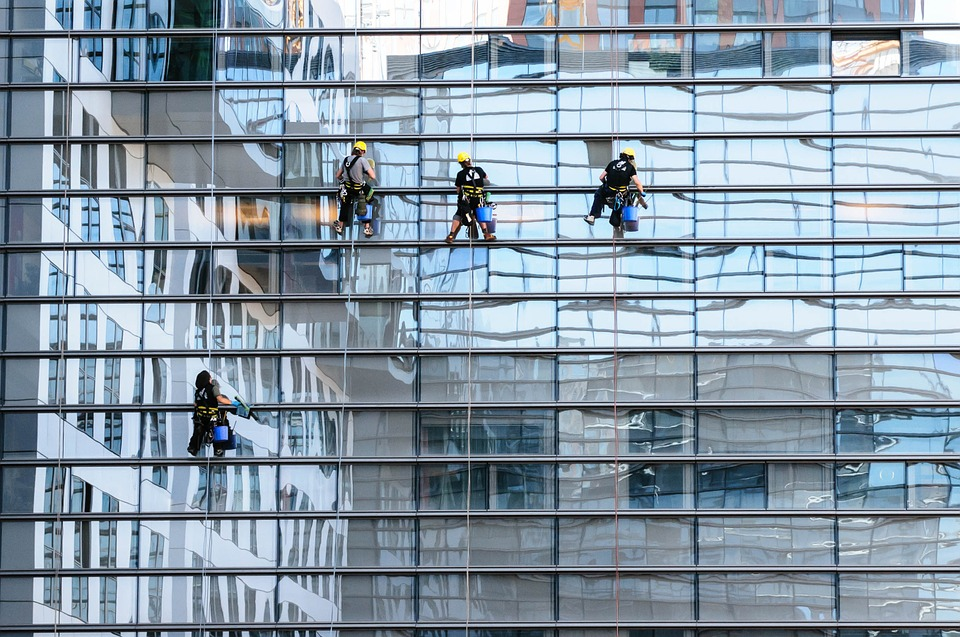Four window cleaners working on a building wearing fall protection equipment