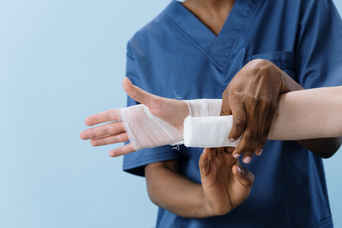 A hand being bandaged by a medical professional