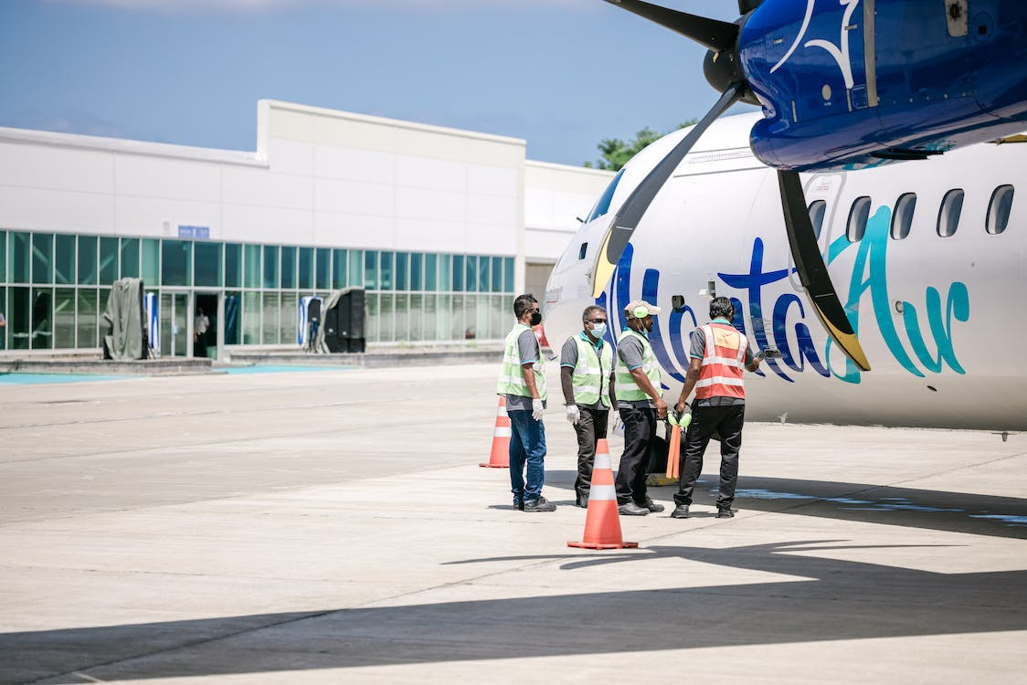 A group of workers in Aviation industry are standing near an airplane in PPE