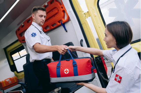 A paramedic is handing over a first aid bag to another paramedic.