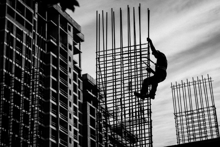 A worker climbing a metal frame without a safety harness