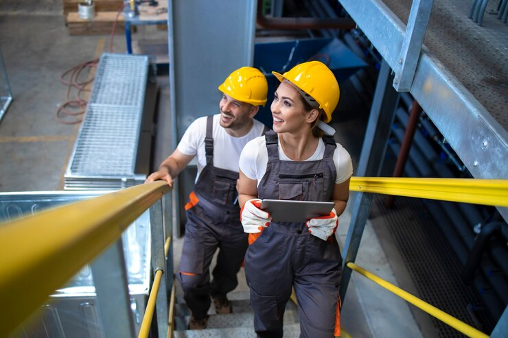 Workers walking in a factory environment and climbing metal stairs.