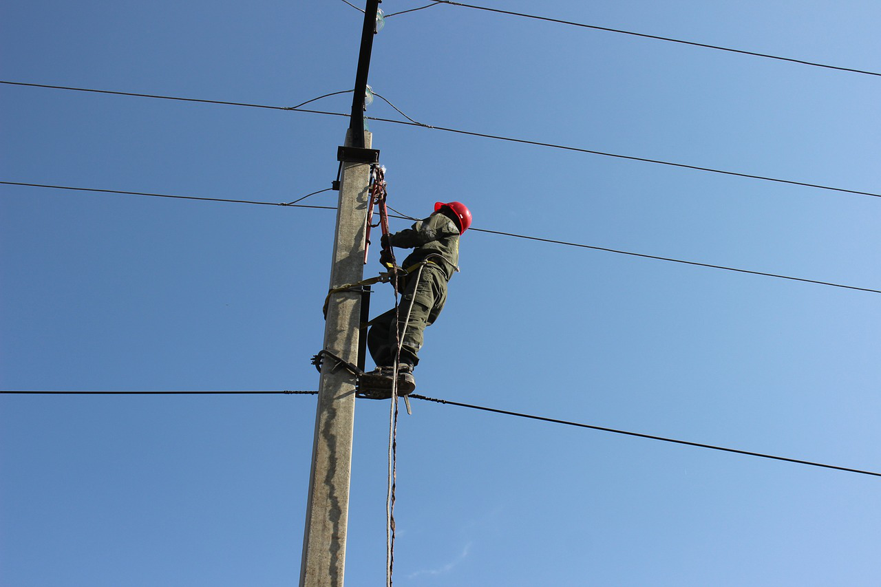 A worker inspecting an electricity pole