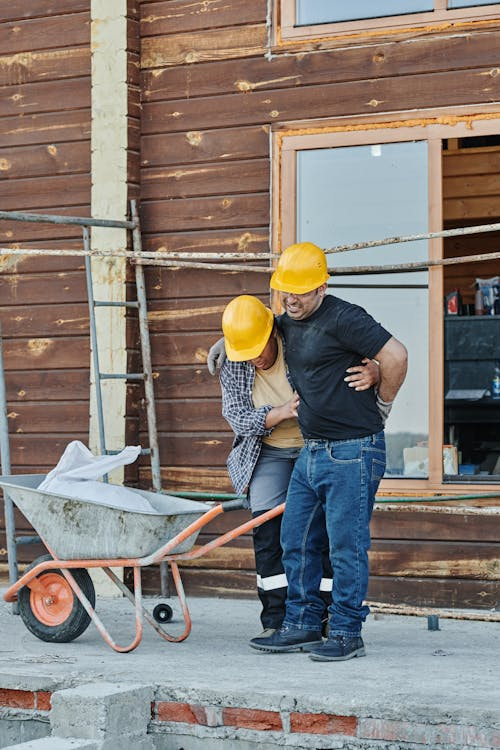 A worker providing assistance by carrying an injured colleague, emphasizing the need for first aid knowledge in handling workplace bone injuries.