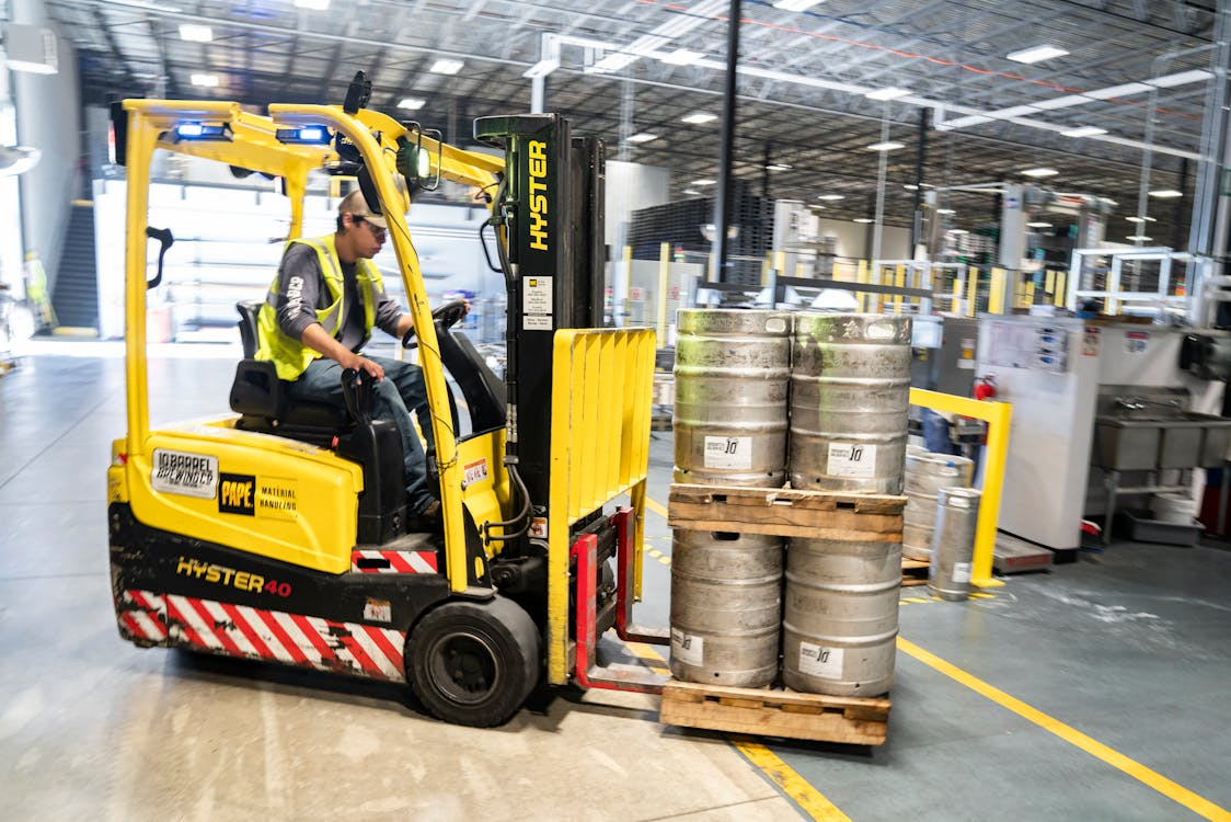 Forklift operator driving a yellow forklift, following safe operation protocols in a warehouse setting.