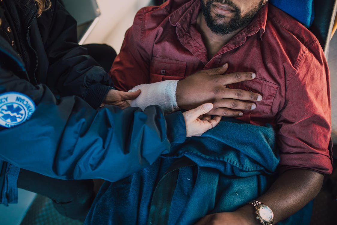 Rescue worker helping a man place his hand on his chest, illustrating first aid training and safety practices.