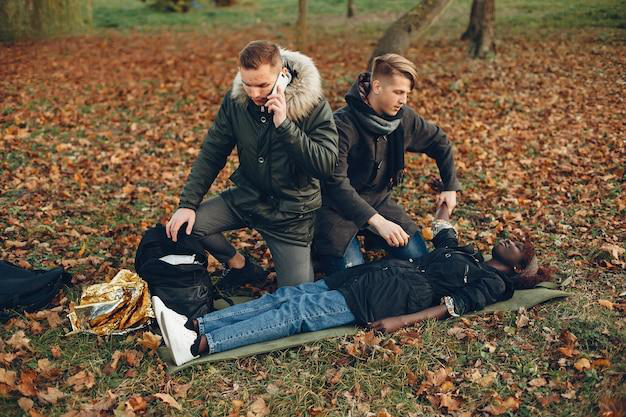 Man calling for an ambulance while providing first aid to an unconscious girl