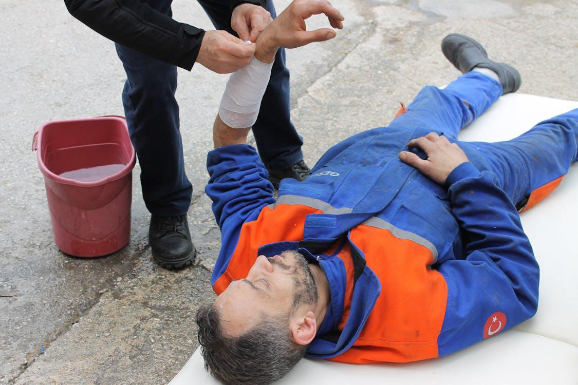 Injured man lying on the ground receiving first aid treatment